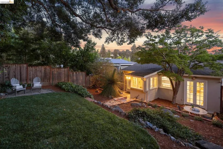 Back of property at dusk with a patio area and a shingled roof