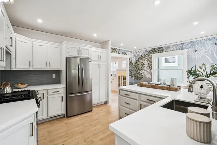 Kitchen with freestanding refrigerator, light wood finished floors, white cabinetry, recessed lighting, and ornamental molding