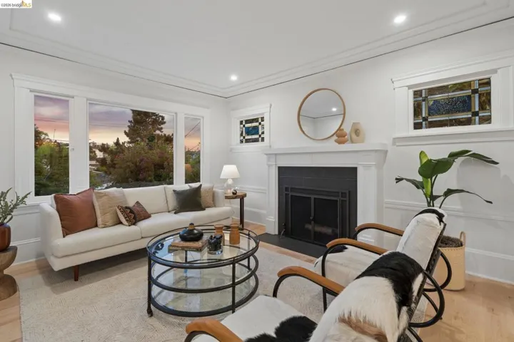 Living room with light wood-style flooring, a fireplace with flush hearth, recessed lighting, ornamental molding, and a decorative wall