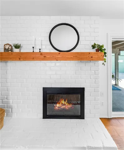 Bright living room with brick fireplace flows seamlessly to dining and covered outdoor entertaining area.