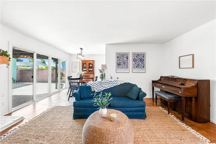 Bright living room with brick fireplace flows seamlessly to dining and covered outdoor entertaining area.
