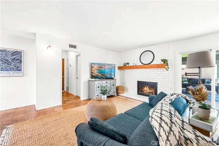 Bright living room with brick fireplace flows seamlessly to dining and covered outdoor entertaining area.