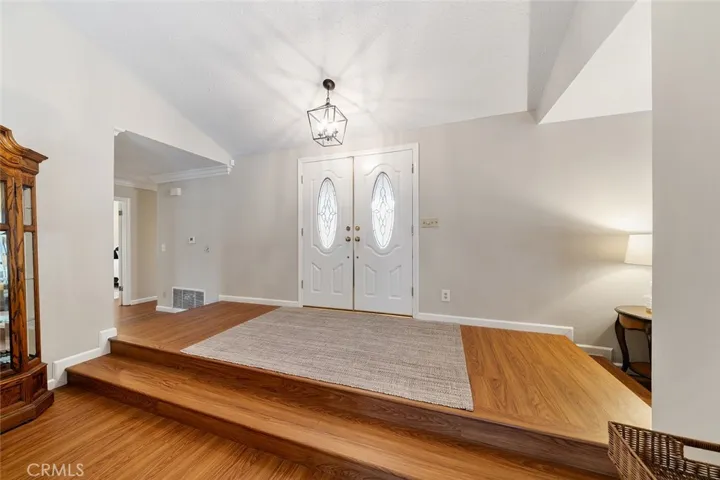 Spacious landing from the double doors and newer light fixture. Left of image leads to the bedrooms and 2 of 3 bathrooms. Right of image leads to the family room. Down the steps leads to the formal living/dining area.