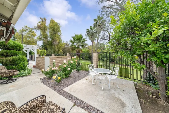 Seating area straight from the primary bedroom retreat area that overlooks the golf course. Pool equipment beyond the block wall left middle of image near the roses.