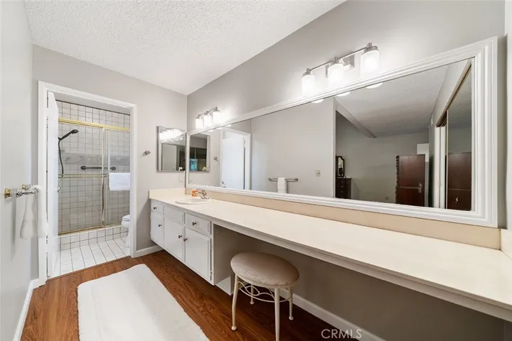 En suite has a nice long counter, newer light fixtures. Private shower and commode in the distance.