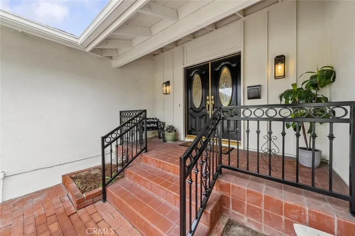 Newly painted double doors and wrought iron and light fixtures adds to the welcome charm of this home.