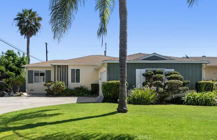 Beautiful curb appeal with lush lawn, tropical landscaping, and long sweeping driveway