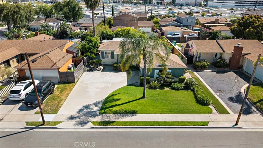 The home boasts inviting curb appeal with a pristine lawn, lush tropical gardens, and a sweeping driveway that accommodates multiple vehicles and leads to a two-car garage.