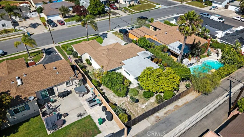 The expansive yard includes multiple patio areas, wide side yards, a variety of fruit trees, and rear alley access through a back gate.