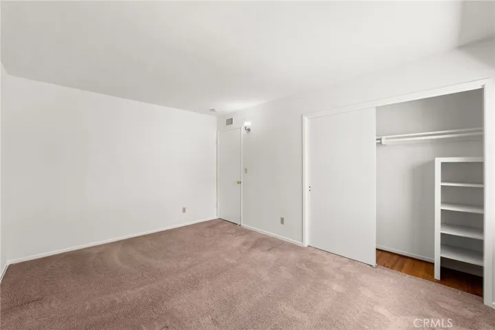 View of same room highlighting closet with built in shelving.