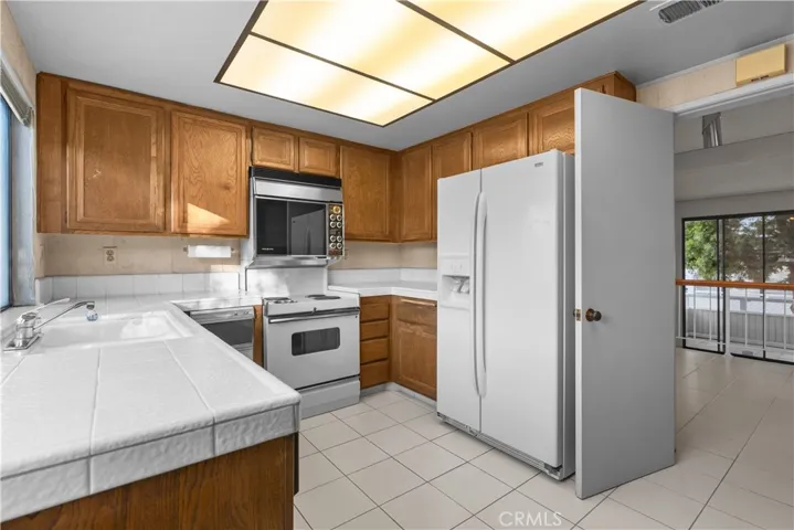 Kitchen with cabinetry and tile countertops, open to the adjacent living area.