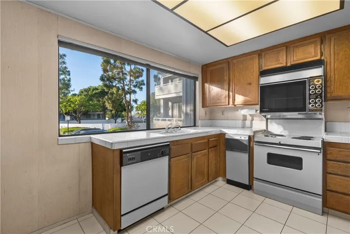 Kitchen with cabinetry, tile countertops, and an oversized window
