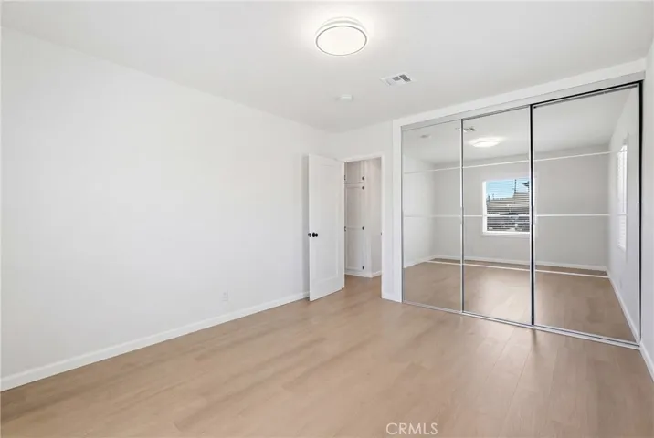 The secondary bedroom features new mirrored closet doors and a custom closet system for enhanced storage and style.