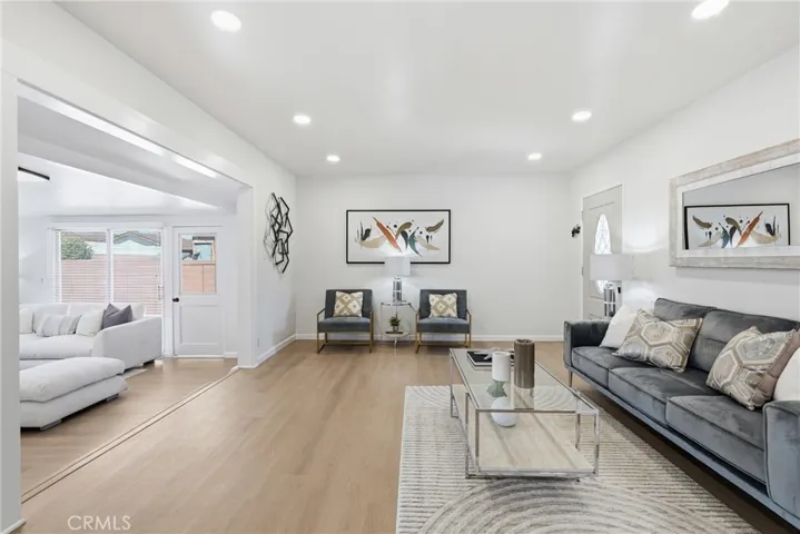The living room flows effortlessly into a versatile den, with both spaces filled with abundant natural light.