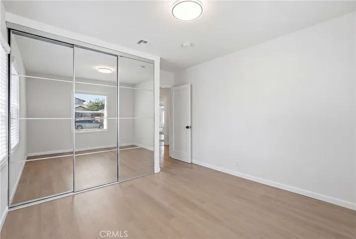 The secondary bedroom features new mirrored closet doors and a custom closet system for enhanced storage and style.