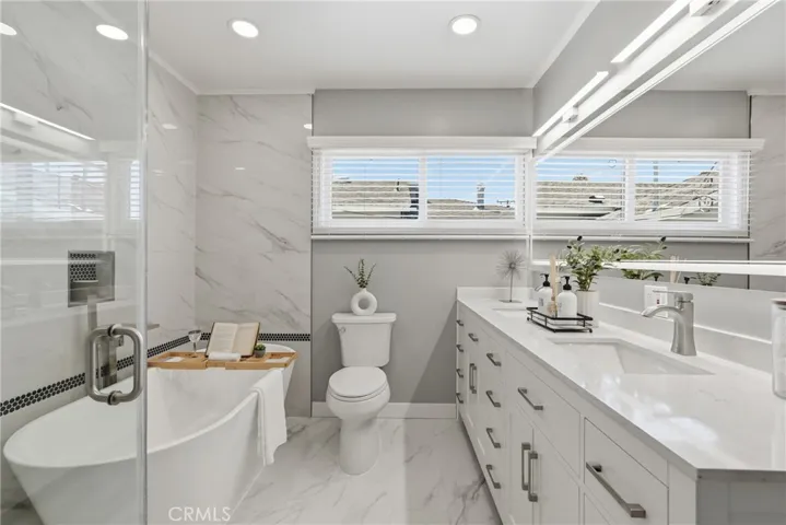 The primary bathroom  features a dual sink vanity, LED mirror, and recessed lighting for a clean, modern feel.