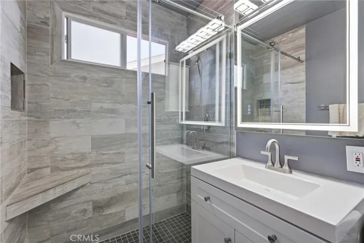 The second bathroom has been beautifully remodeled, featuring an updated vanity, LED mirror, porcelain tile shower floor, and sleek frameless sliding glass doors.