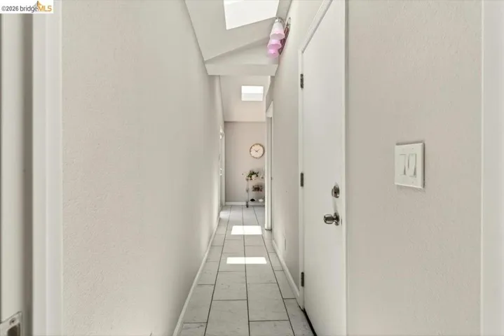 Hallway with lofted ceiling and a textured wall