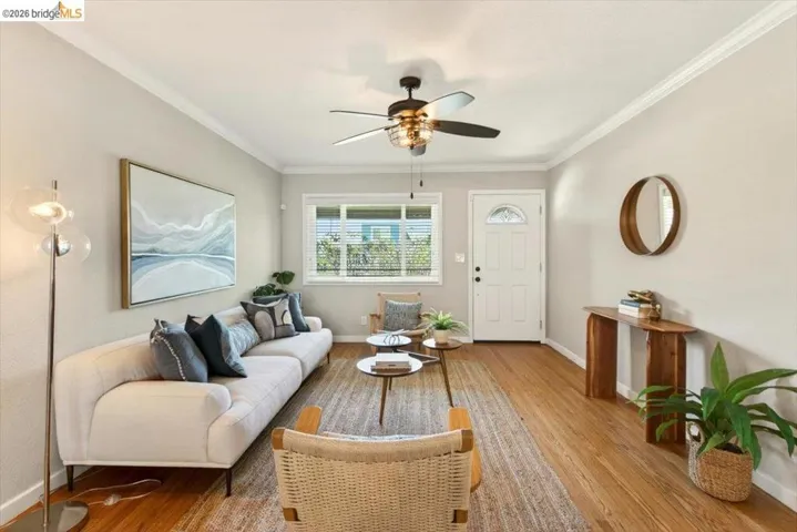 Living room featuring a ceiling fan, wood finished floors, and ornamental molding