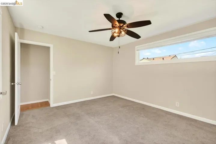Spare room featuring light colored carpet and a ceiling fan