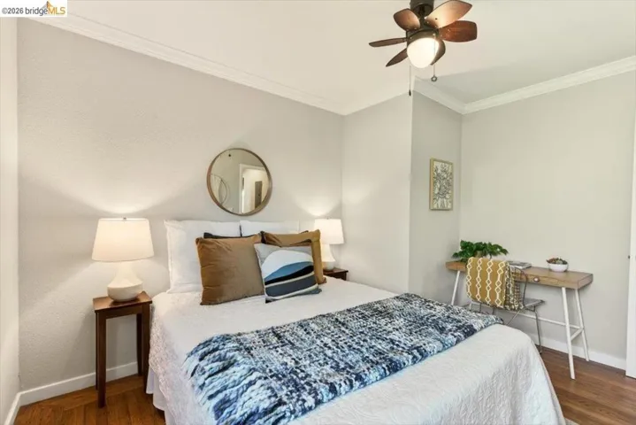 Bedroom with ornamental molding, dark wood-type flooring, and ceiling fan