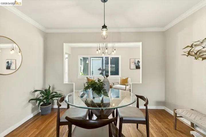 Dining area with ornamental molding, wood finished floors, and suspended lighting