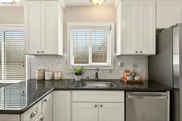 Kitchen with dark stone counters, stainless steel appliances, and white cabinets
