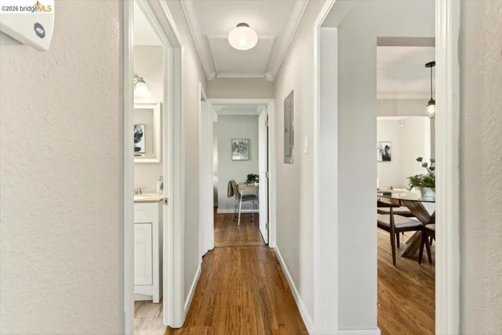 Hallway with a textured wall, ornamental molding, and wood finished floors