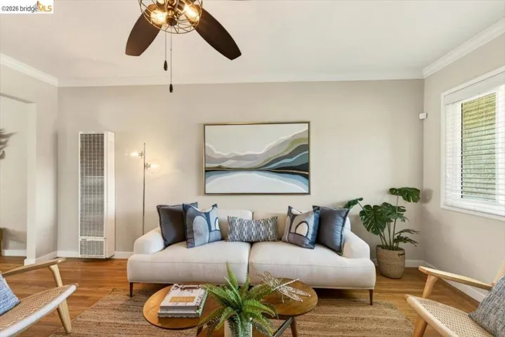 Living area featuring wood finished floors, crown molding, a heating unit, and ceiling fan