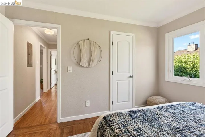 Bedroom with crown molding, wood finished floors, and electric panel