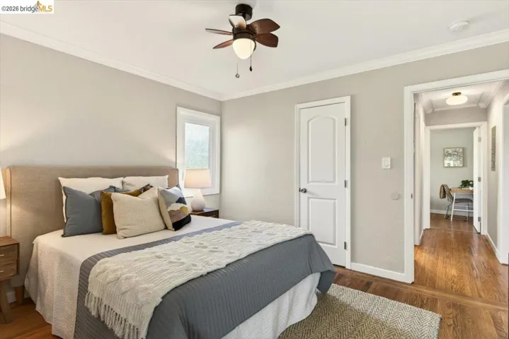 Bedroom featuring crown molding, dark wood-style floors, and a ceiling fan