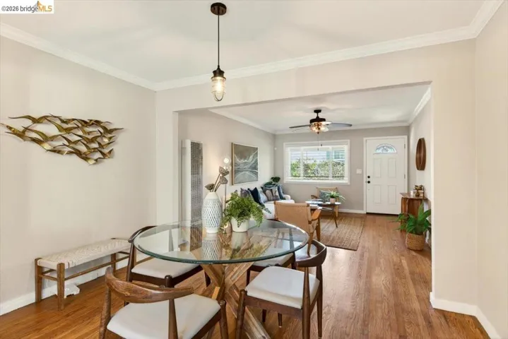 Dining room with wood finished floors, ornamental molding, a ceiling fan, and a heating unit