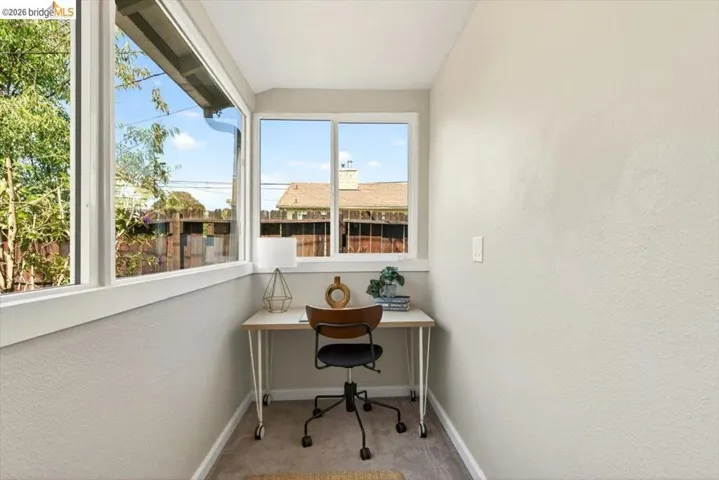 Home office featuring light colored carpet and a textured wall