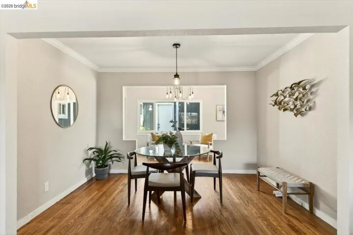 Dining area with wood finished floors, crown molding, and hanging lights
