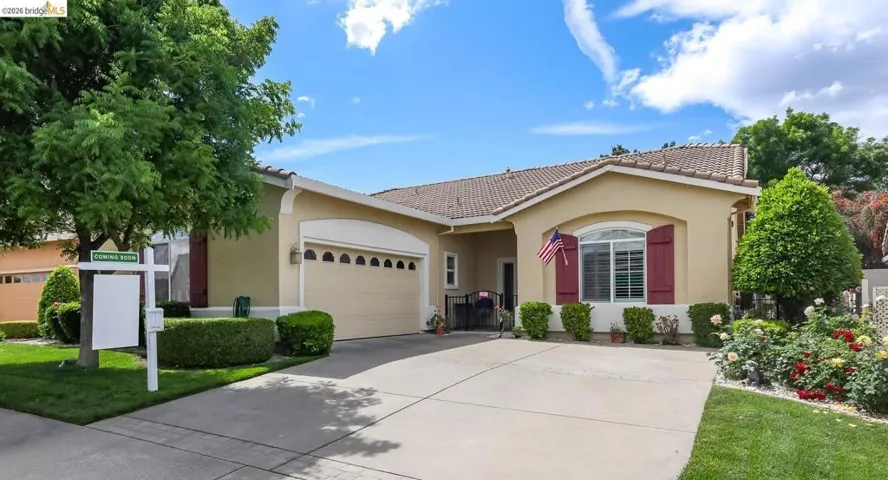 View of front of home featuring a garage, stucco siding, a tile roof, and driveway