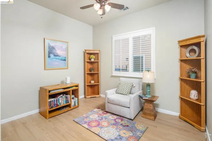 Living area with light wood-style floors and a ceiling fan