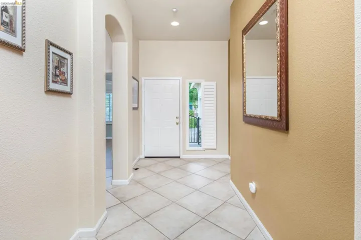 Entryway featuring a textured wall, arched walkways, light tile patterned floors, and recessed lighting
