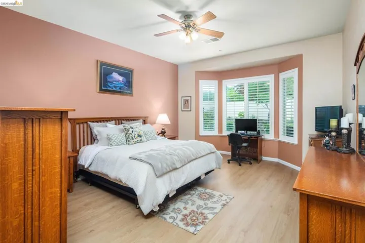 Bedroom with a desk, light wood-style floors, and a ceiling fan