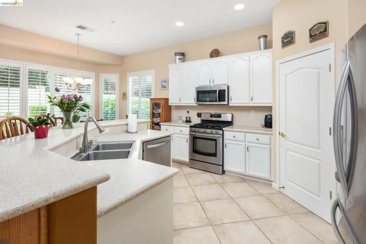 Kitchen with stainless steel appliances, white cabinetry, tasteful backsplash, a center island with sink, and light tile patterned flooring