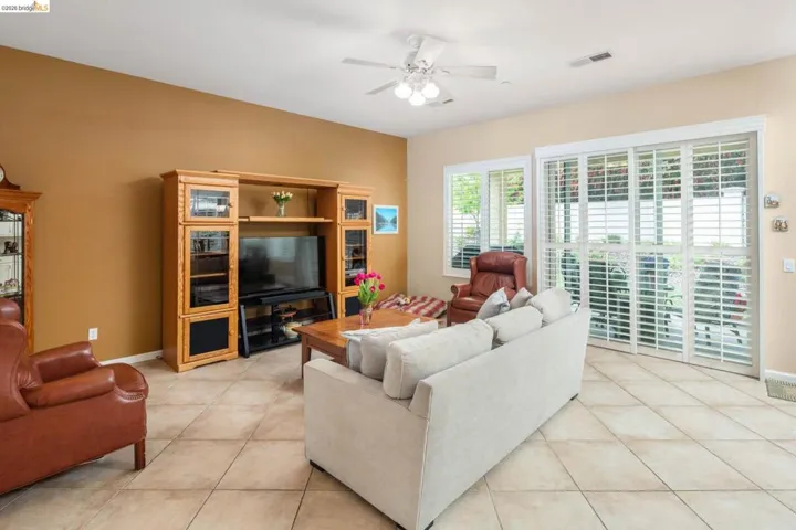 Living room with a ceiling fan and light tile patterned floors
