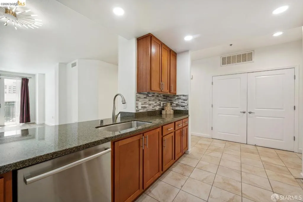 Kitchen featuring a peninsula with a stainless steel undermount sink, a gooseneck faucet, and a built-in dishwasher