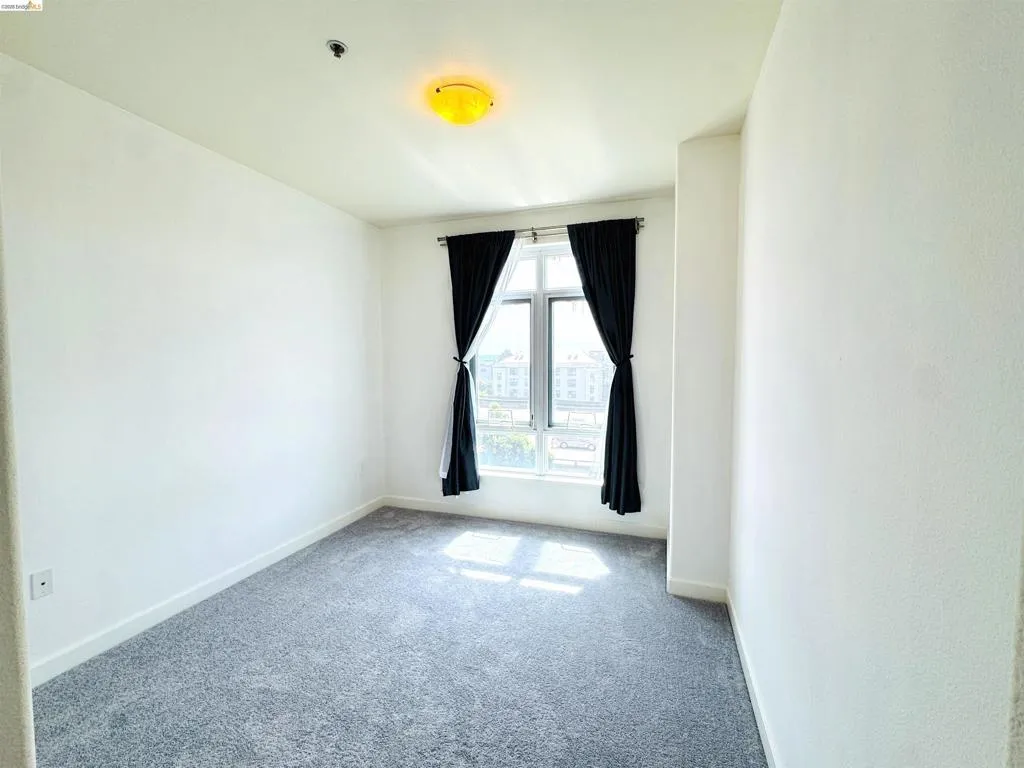 Empty room with light colored carpet and baseboards