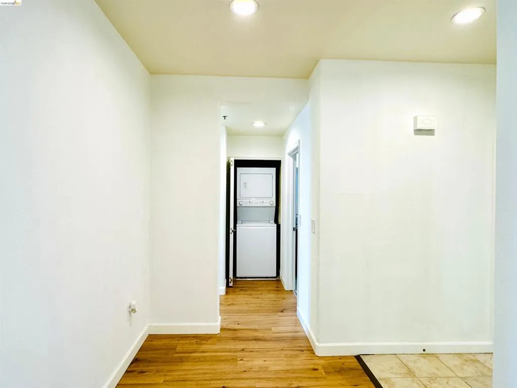Corridor featuring recessed lighting, light wood-type flooring, and stacked washer and dryer