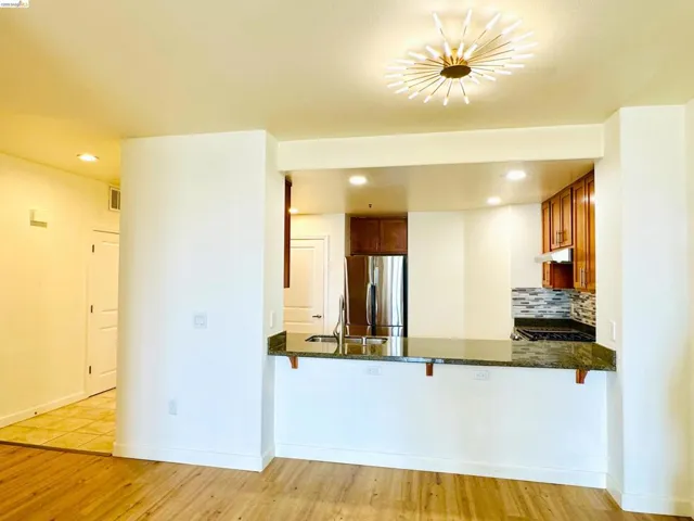 Kitchen featuring a breakfast bar area, wood finish cabinets, freestanding refrigerator, tasteful backsplash, and dark stone countertops