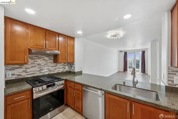 Kitchen featuring wood cabinetry, stainless steel appliances, a tile backsplash, and a double basin sink