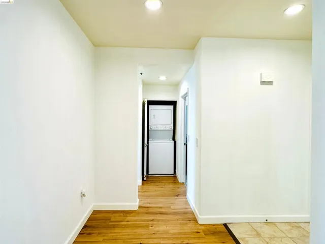 Corridor featuring recessed lighting, light wood-type flooring, and stacked washer and dryer