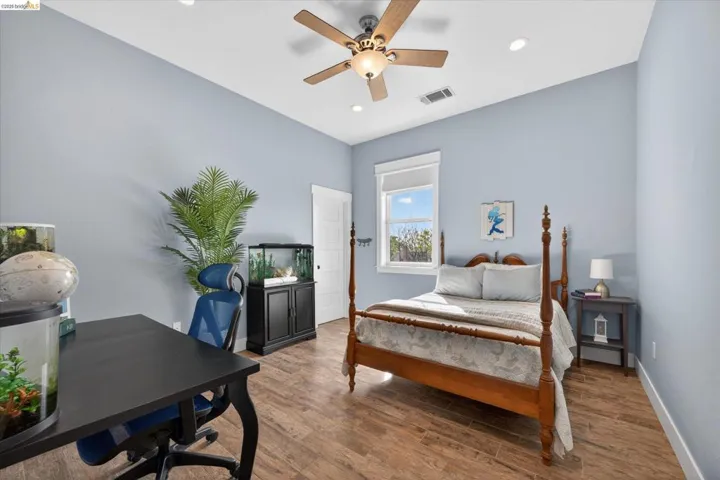 Bedroom featuring wood finished floors, a desk, ceiling fan, and recessed lighting, walk in closet