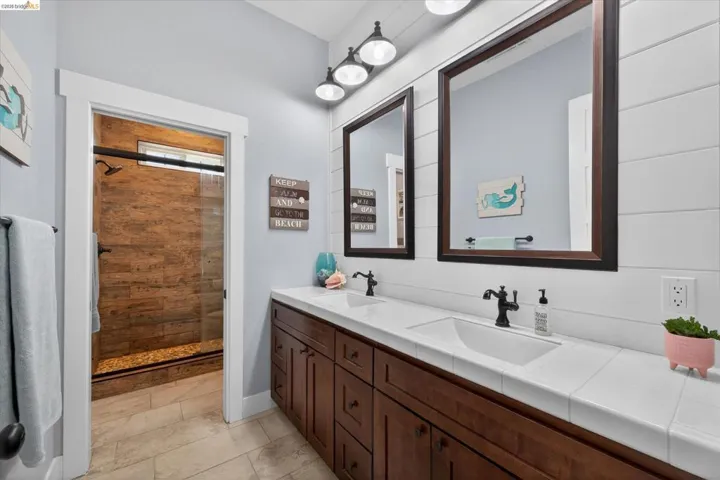 Full bathroom with double vanity and a stall shower
