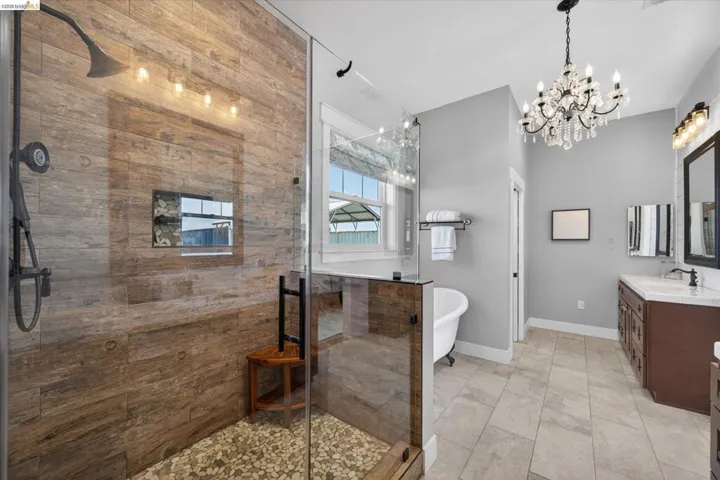 Bathroom with vanity, a soaking tub, a stall shower, and a chandelier