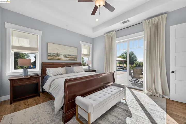 Bedroom featuring access to outside, a tray ceiling, wood finished floors, a ceiling fan, and recessed lighting